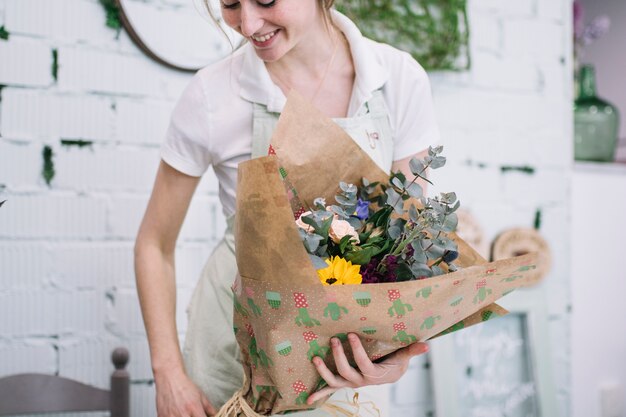 Smiling florist with wrapped bouquet