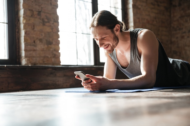 Free photo smiling focused sportsman using mobile phone