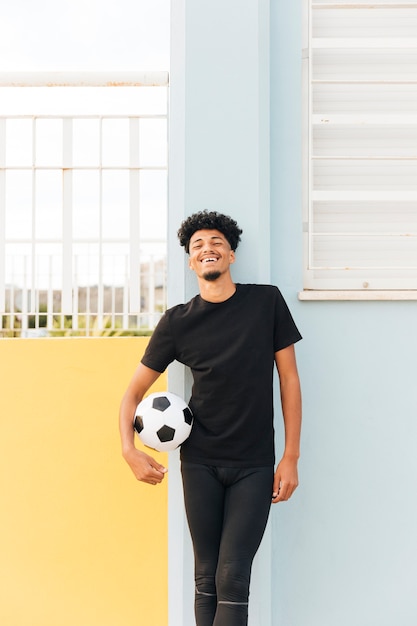 Free photo smiling football player holding ball and looking at camera