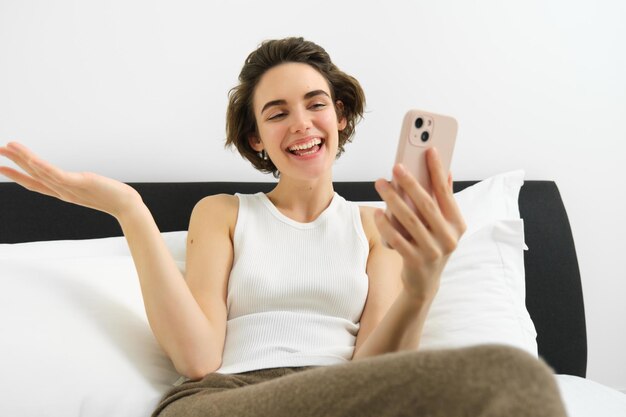 Smiling friendly young woman chatting on smartphone app talking via video call app on mobile phone