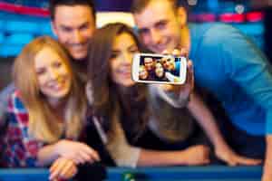 Free photo smiling friends taking selfie photo from nightclub with billiard