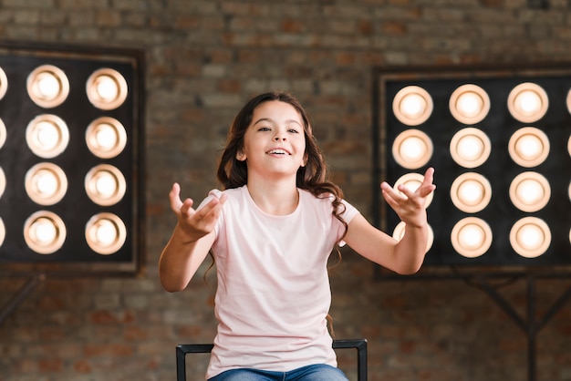 Smiling girl acting in studio with stage light in the background