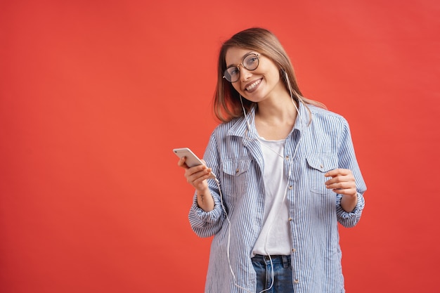 Smiling girl in casual clothes and earphones dancing moving hands.