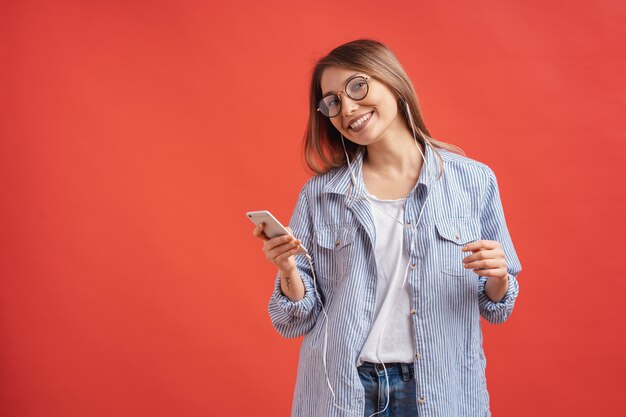 カジュアルな服装とイヤホンが手を動かすダンスの笑顔の女の子。