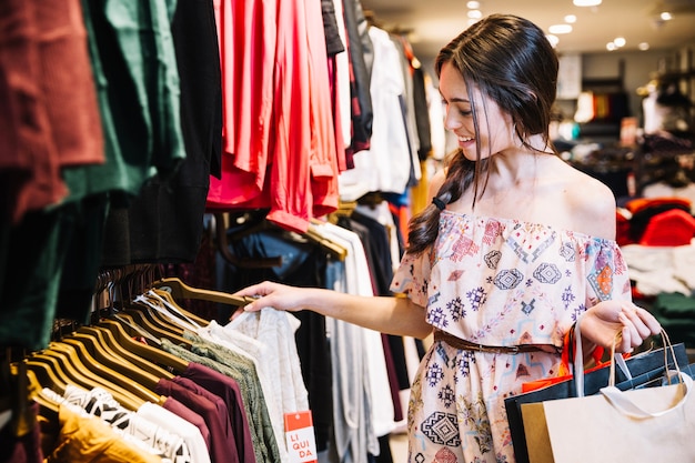 Premium Photo | Smiling girl in clothing shop choosing