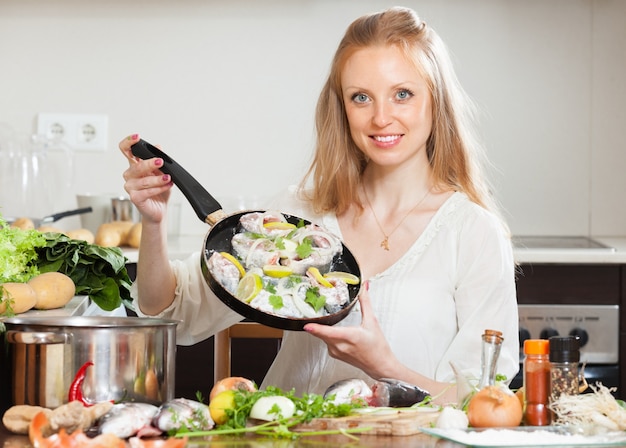 Free photo smiling girl cooking fish with lemon
