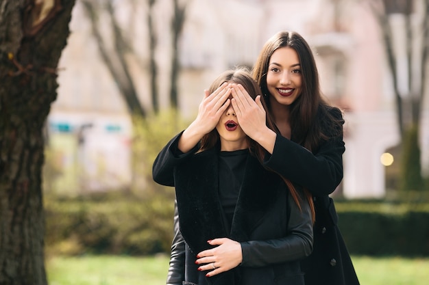 Smiling girl covering her friend's eyes