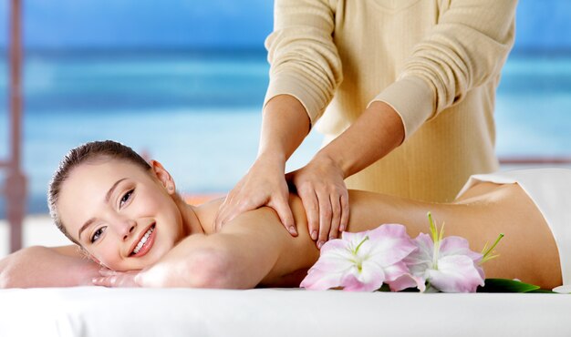 Smiling girl  getting spa massage in beauty salon - nature space. Indoors