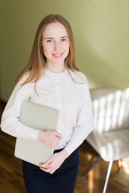 Ragazza sorridente afferrare un computer portatile