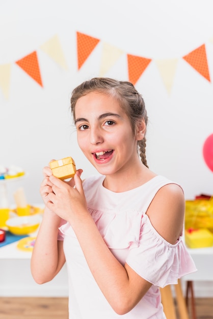 Smiling girl holding birthday gift during party