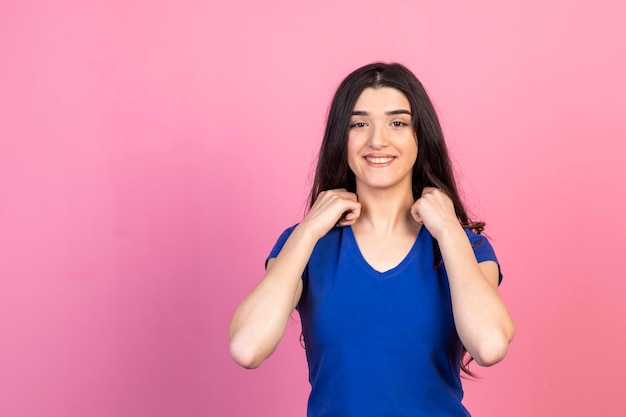 Smiling girl holding her hands to her neck and smiling