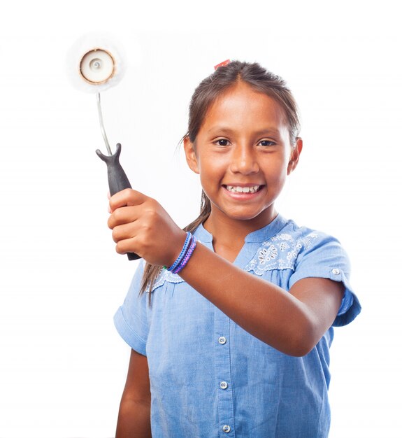 Smiling girl holding a paint roller aside