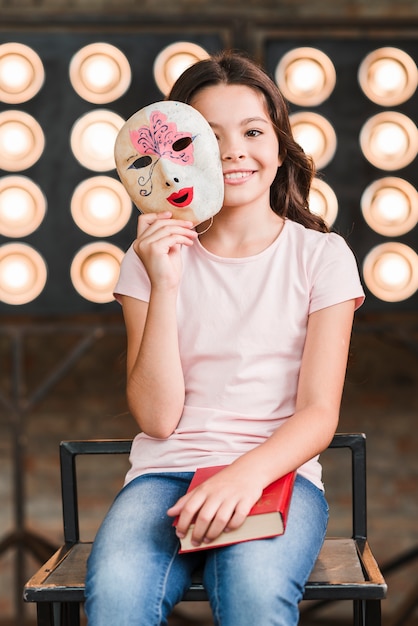 Free photo smiling girl holding venetian mask in her hands