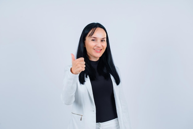 Smiling girl is lokking at camera by showing perfect gesture on white background