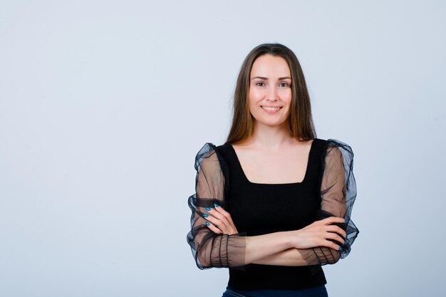 Smiling girl is looking at camera by crossing arms on white background