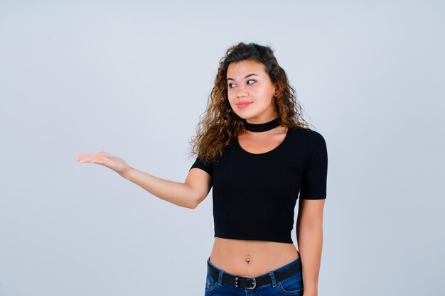 Smiling girl is looking down by pointing left with hand on white background