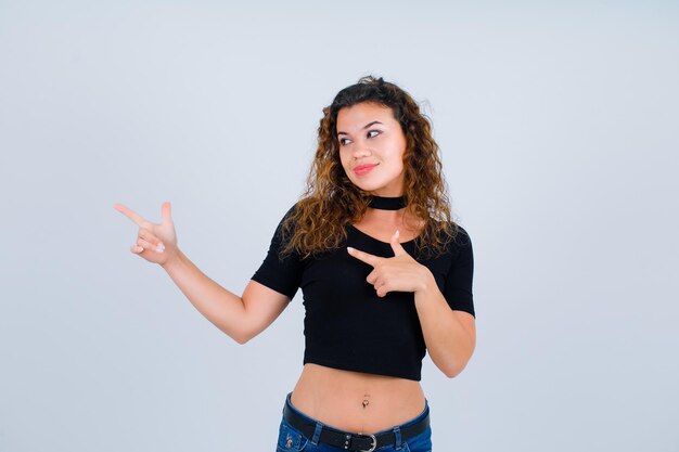 Smiling girl is looking left by pointing left with forefingers on white background