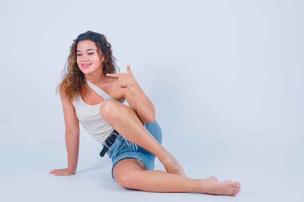 Smiling girl is pointing left with forefinger on white background