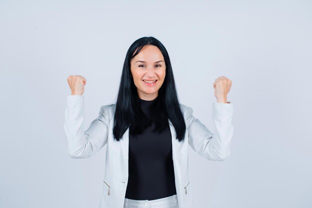 Smiling girl is raising up her fists on white background