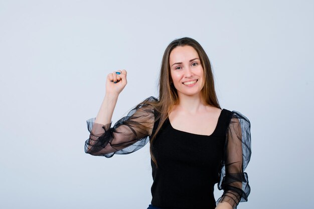 Smiling girl is showing he fist by raising up it on white background