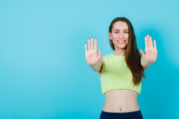 Smiling girl is showing he rhandfuls to camera by extending hands on blue background