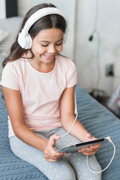 Smiling girl listening music on headphone through digital tablet