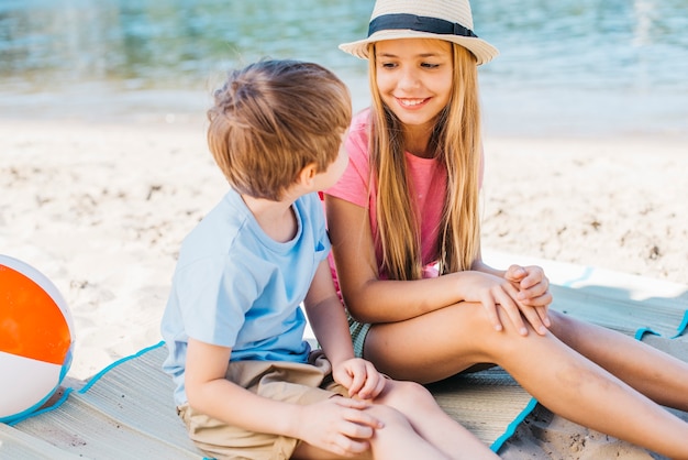 Бесплатное фото Улыбающаяся девушка смотрит на мальчика счастливо на побережье