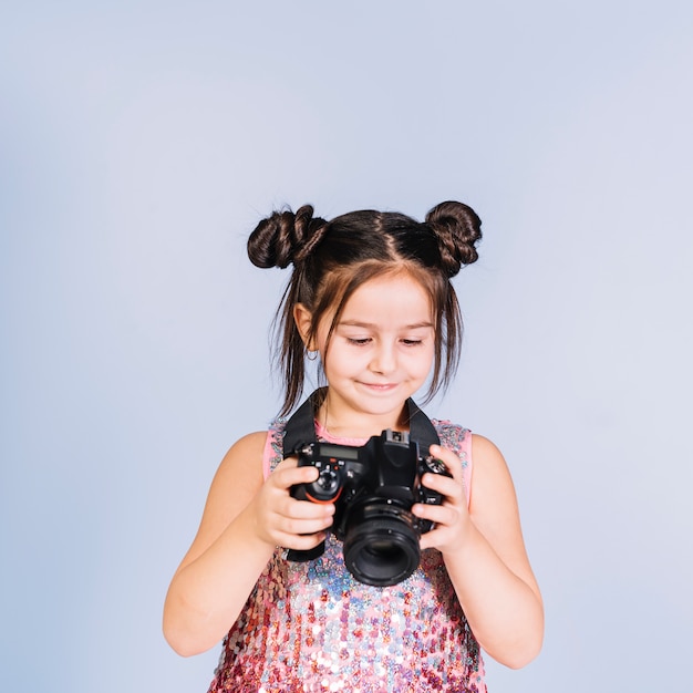 Smiling girl looking at digital camera against blue background