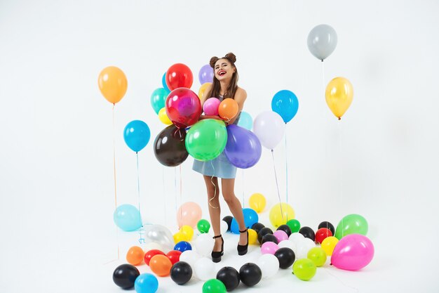 Smiling girl looks happy holding bunch of big balloons