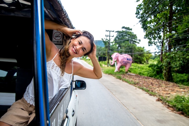 Free photo smiling girl looks out of the window of a taxi, tuk-tuk travel concept