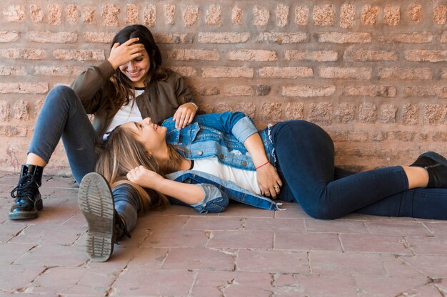 Smiling girl lying on her friends lap while having fun