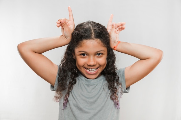 Free photo smiling girl making horn gesture against white background