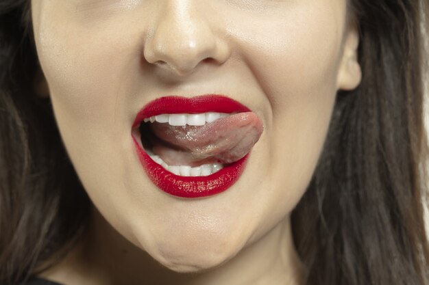 Ragazza sorridente aprendo la bocca e mostrando la lunga grande lingua gigante su bianco.