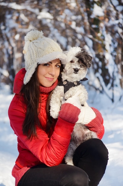 Sorridente ragazza in posa con il suo cane in campo nevoso