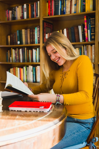 Smiling girl reading book in library