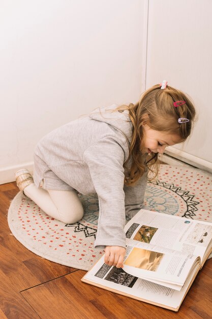 Free photo smiling girl reading on floor