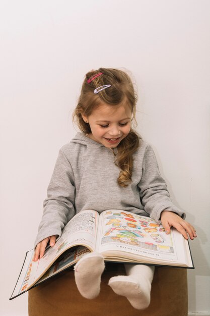 Smiling girl reading on pouf