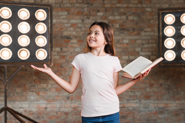 Smiling girl rehearsing in studio holding an open book