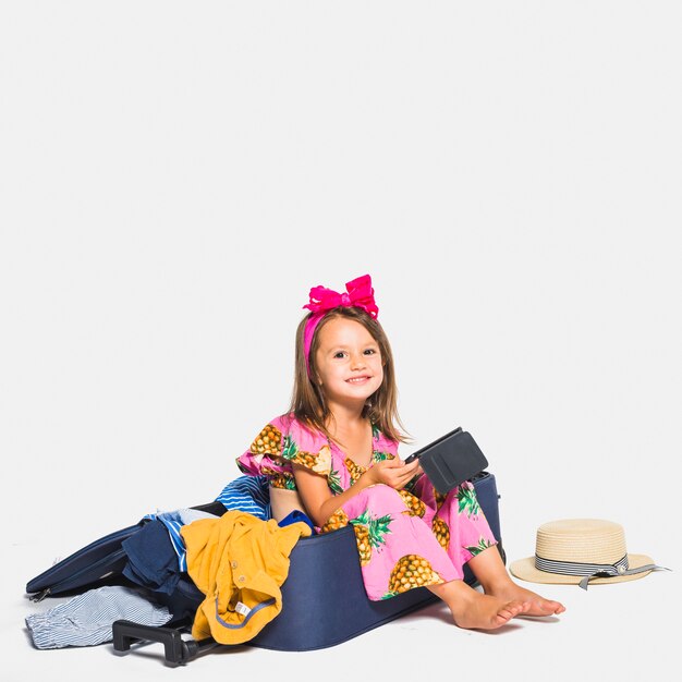 Smiling girl sitting on suitcase