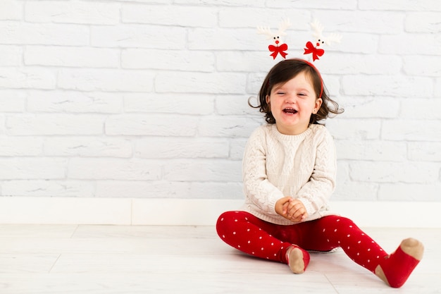 Smiling girl sitting next to white wall