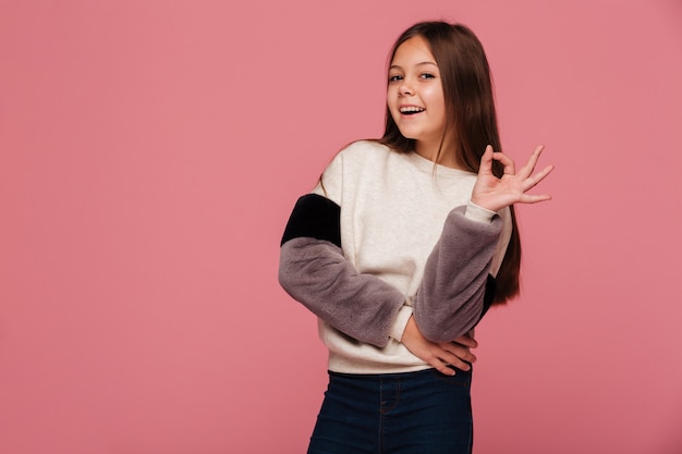 Free photo smiling girl in sweater looking and showing ok gesture
