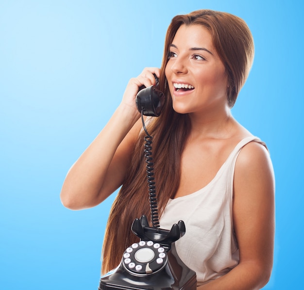 Ragazza sorridente che comunica sopra il telefono vecchio stile