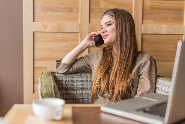 Sorridente ragazza parla al telefono in un negozio di caffè