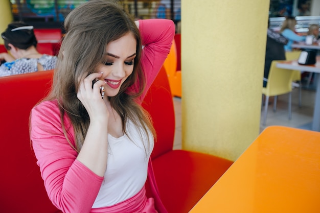 Free photo smiling girl touching her hair while talking on the phone