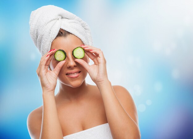 Smiling girl in towel with cucumber eye mask