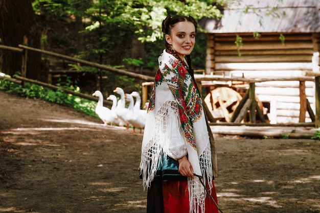 Smiling girl in a Ukrainian embroidered dress is walking around the yard