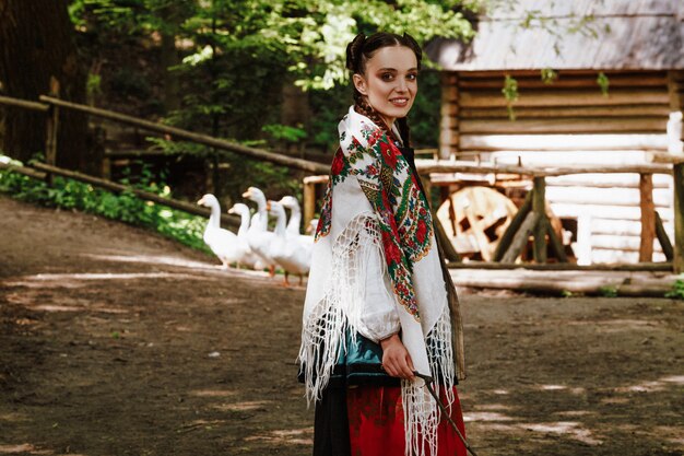 Smiling girl in a Ukrainian embroidered dress is walking around the yard