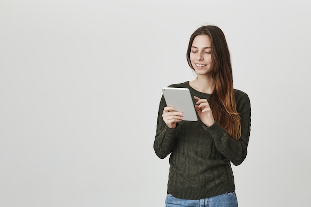 La ragazza sorridente che utilizza la compressa digitale, pubblica l'immagine nell'app