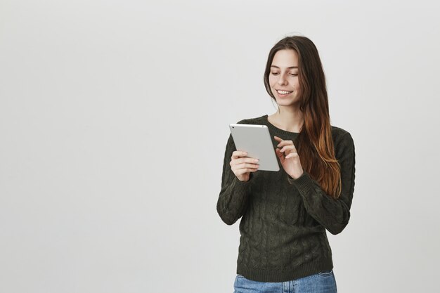 Smiling girl using digital tablet, edit picture in app
