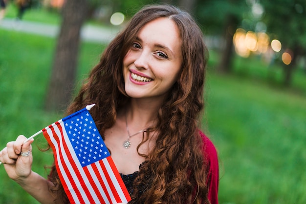 Foto gratuita ragazza sorridente con la bandiera americana in natura